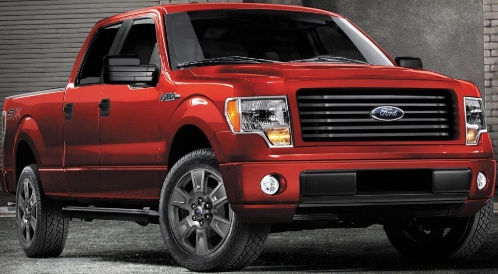 A red 2014 Ford F-150 STX parked in front of a garage.