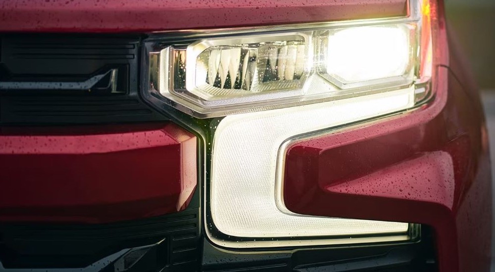 A closeup shows the drivers side headlight on a red 2022 Chevy Silverado 1500.