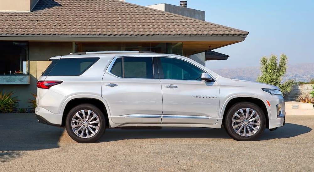 A silver 2021 Chevy Traverse parked in the driveway of a desert home overlooking hills.