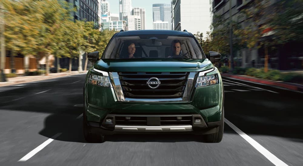 A green 2022 Nissan Pathfinder is shown from the front driving on a city street.