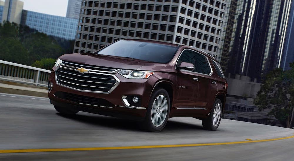 A maroon 2020 Chevy Traverse driving on a city highway.