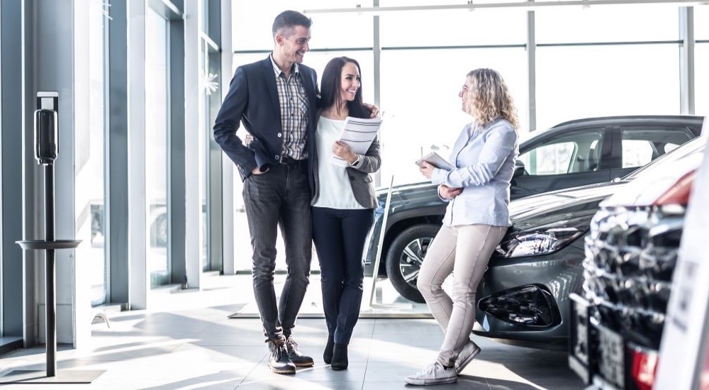 A couple talking to a salesperson at a dealership.