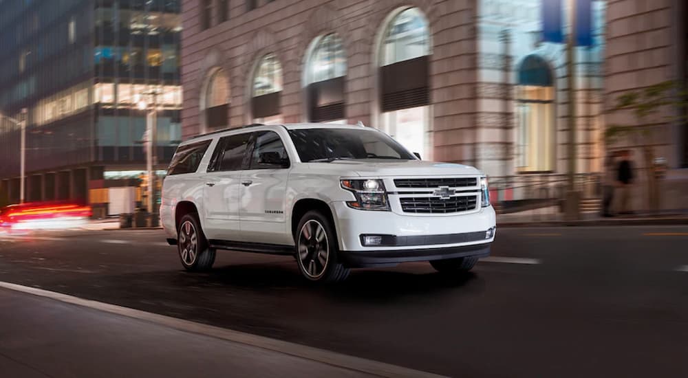 A white 2020 Chevy Suburban purchased from a used car dealer driving on a city street at night.
