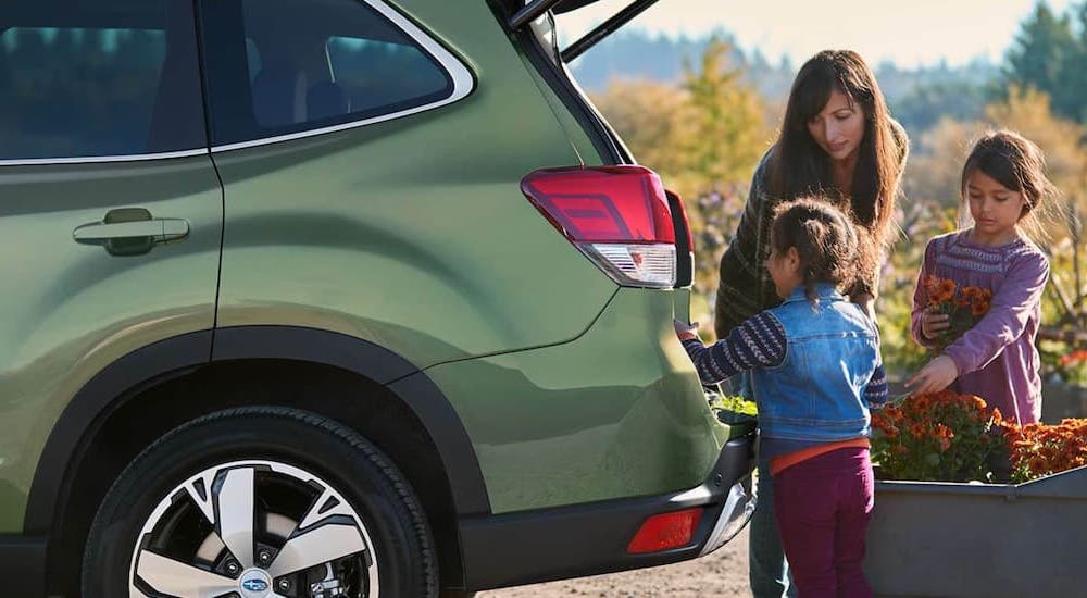 A family putting fresh-picked flowers into the back of a green 2021 Subaru Forester.