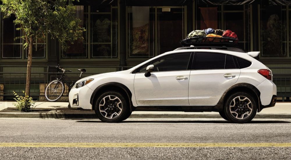 Side view of a white 2016 Subaru Crosstrek with cargo on the roof.