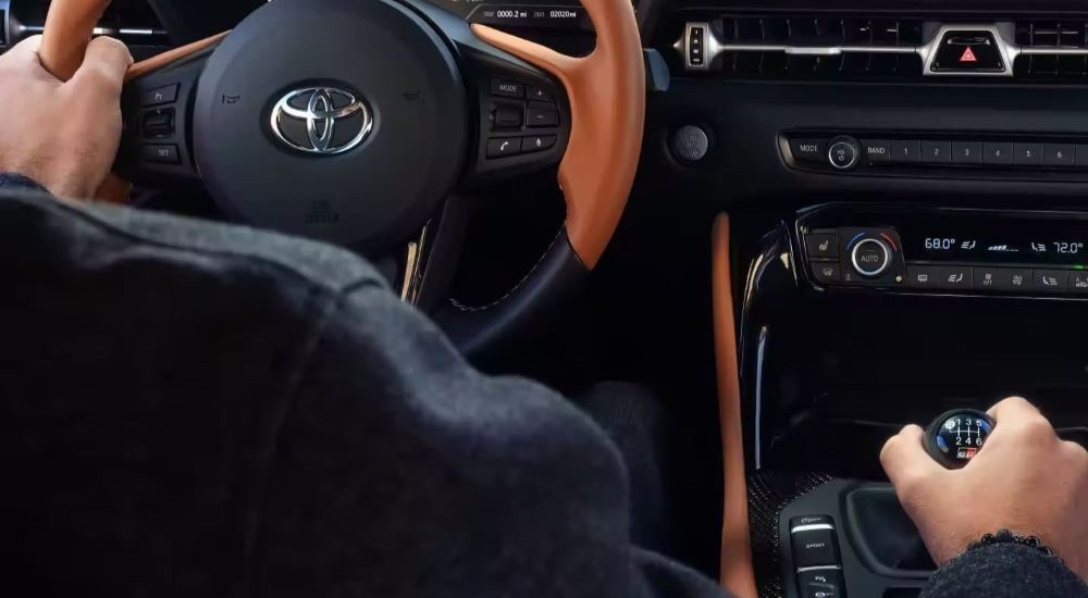 The black and brown leather interior of a 2021 Toyota GR Supra at a used sports car dealer.